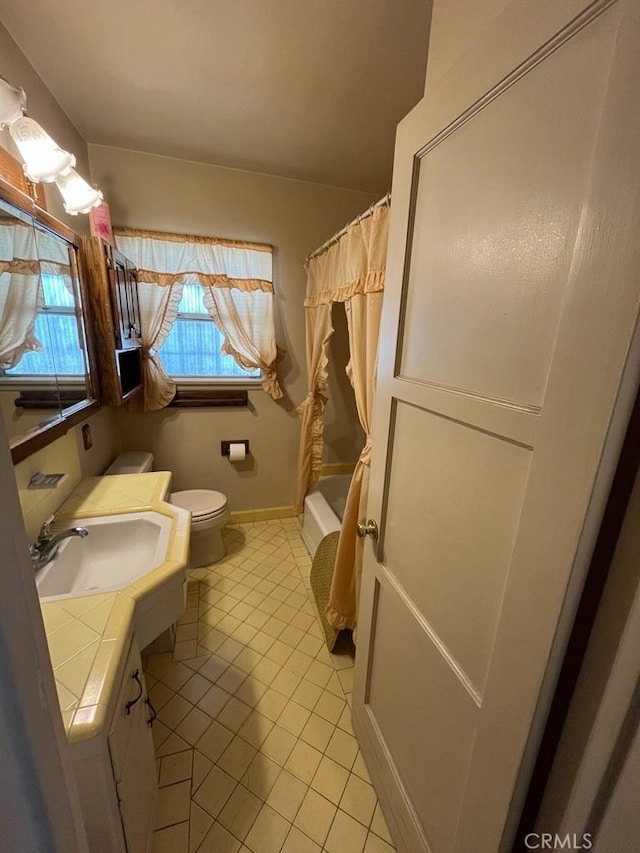 full bathroom with tile patterned floors, toilet, vanity, shower / tub combo with curtain, and baseboards