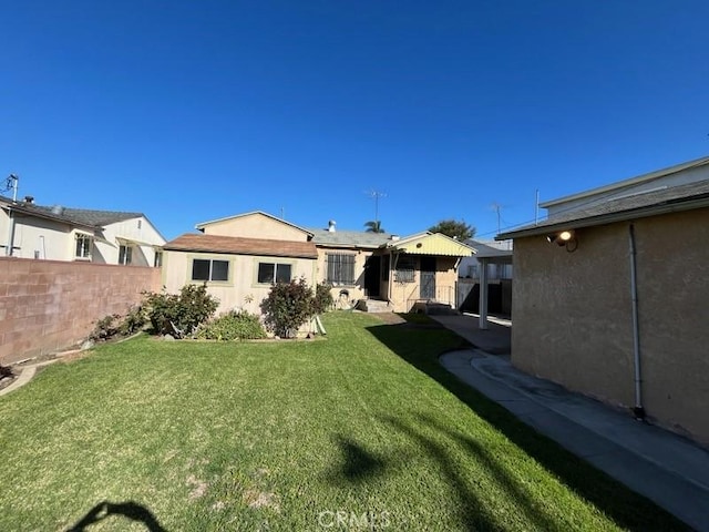 back of house with a lawn, fence, and stucco siding