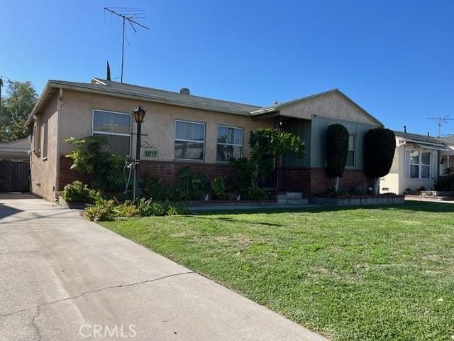 single story home featuring an attached carport, concrete driveway, brick siding, a front yard, and stucco siding