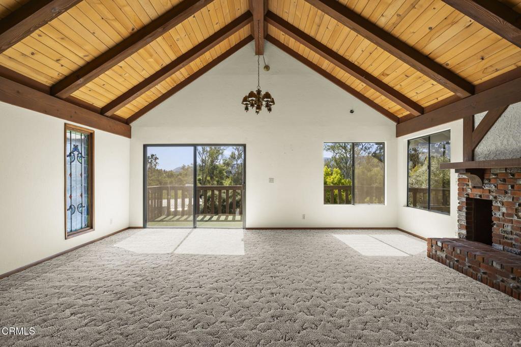 275 Fairview Rd, Ojai, CA 93023 - unfurnished living room with baseboards, carpet floors, a brick fireplace, beamed ceiling, and high vaulted ceiling