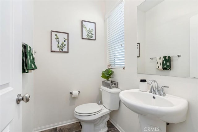half bath with a sink, toilet, and baseboards
