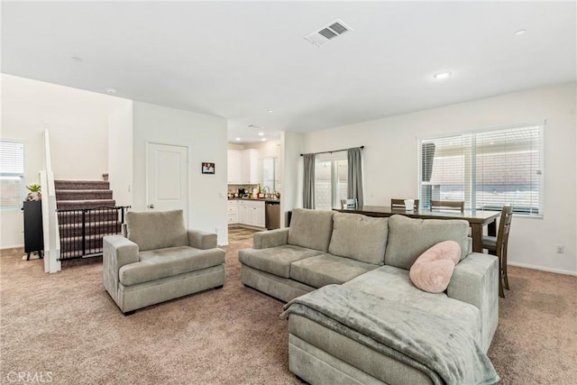 living room featuring visible vents, baseboards, recessed lighting, and light colored carpet