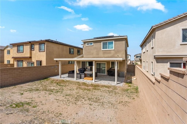 back of house with a patio, solar panels, a fenced backyard, and stucco siding