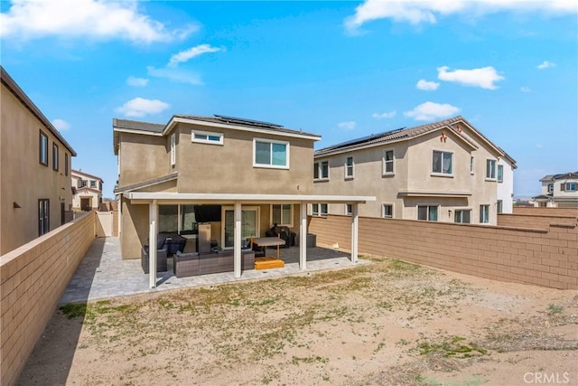 back of property featuring a patio, a fenced backyard, stucco siding, and roof mounted solar panels