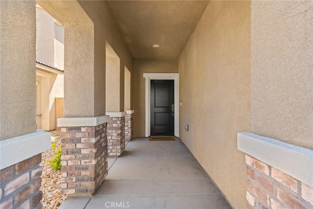 entrance to property featuring stone siding and stucco siding