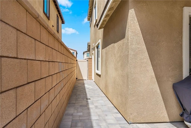 view of side of home with fence and stucco siding