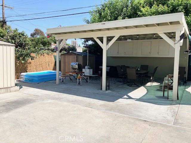 242 E 116th St, Los Angeles, CA 90061 - view of patio featuring fence, outdoor dining space, an outbuilding, and a storage shed