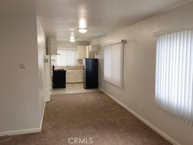 242 E 116th St, Los Angeles, CA 90061 - interior space with white cabinets, freestanding refrigerator, light carpet, and baseboards