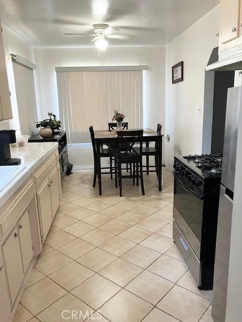 242 E 116th St, Los Angeles, CA 90061 - kitchen featuring ceiling fan, light countertops, freestanding refrigerator, gas range, and light tile patterned flooring