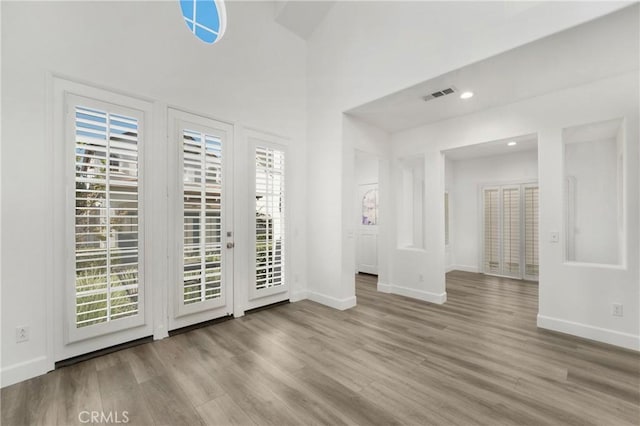 interior space with visible vents, access to exterior, wood finished floors, and baseboards