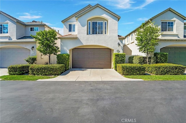 view of front of house with an attached garage, concrete driveway, and stucco siding