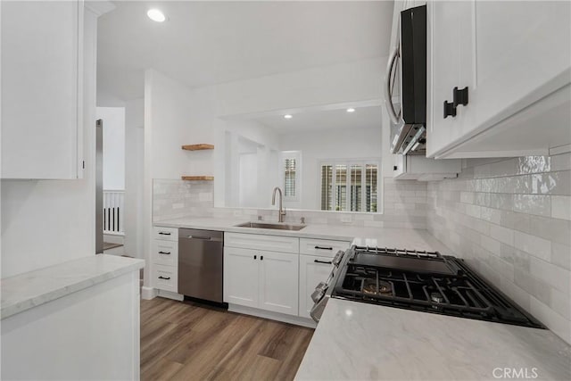 kitchen with tasteful backsplash, white cabinets, a sink, appliances with stainless steel finishes, and light stone counters
