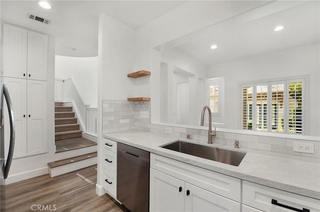 kitchen featuring light wood-style flooring, open shelves, visible vents, stainless steel dishwasher, and a sink