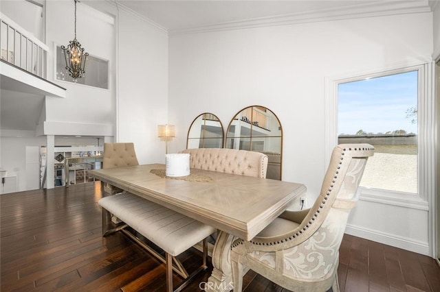 dining space with dark wood-style flooring, baseboards, ornamental molding, a fireplace, and a chandelier
