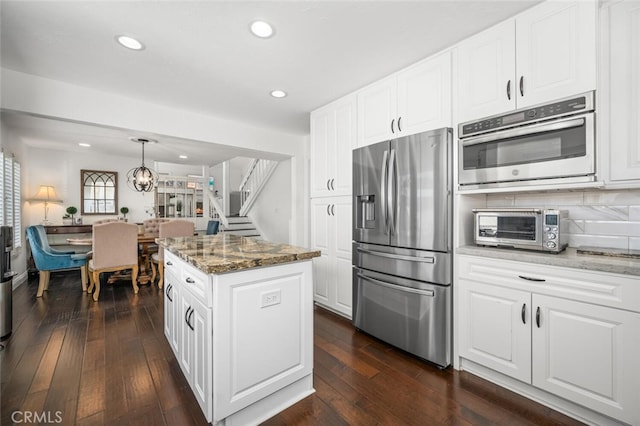kitchen featuring stainless steel appliances, light stone countertops, a kitchen island, dark wood-style flooring, and recessed lighting