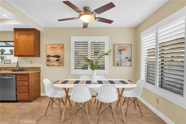 dining space with light tile patterned floors, baseboards, a ceiling fan, and a textured ceiling