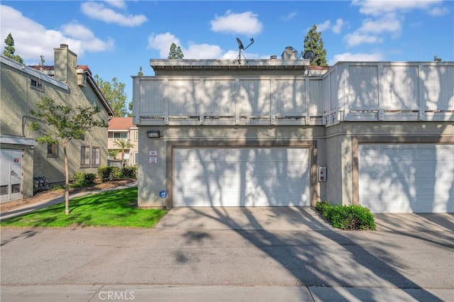 view of front of house with a balcony, a garage, driveway, and stucco siding