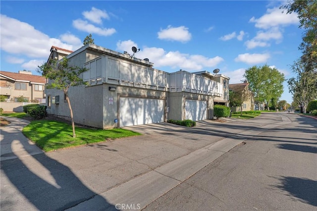 exterior space with concrete driveway, a balcony, and stucco siding
