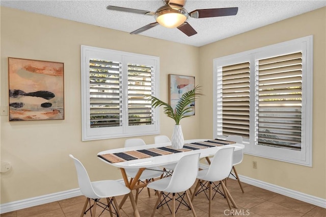 tiled dining area with a textured ceiling, baseboards, and a ceiling fan