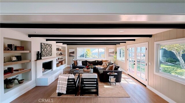 4903 Spencer St, Torrance, CA 90503 - living room with built in features, beamed ceiling, a fireplace with raised hearth, wood finished floors, and wooden walls
