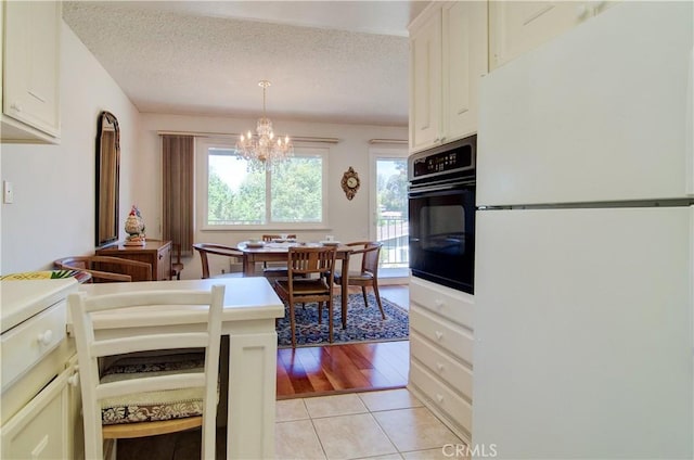 606 Avenida Sevilla Unit O, Laguna Woods, CA 92637 - kitchen with a notable chandelier, freestanding refrigerator, a textured ceiling, black oven, and light tile patterned flooring