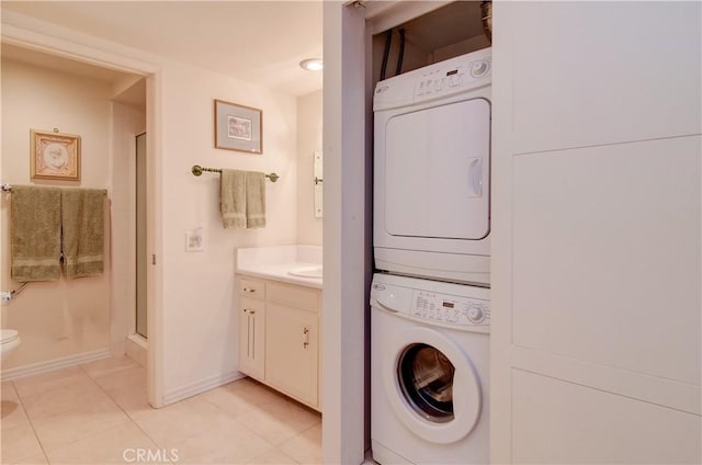 606 Avenida Sevilla Unit O, Laguna Woods, CA 92637 - washroom featuring stacked washer and dryer, baseboards, light tile patterned flooring, and laundry area