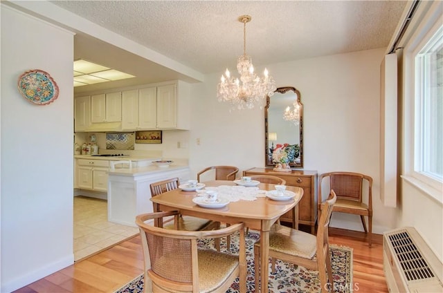 606 Avenida Sevilla Unit O, Laguna Woods, CA 92637 - dining area featuring light wood finished floors, a chandelier, and a textured ceiling