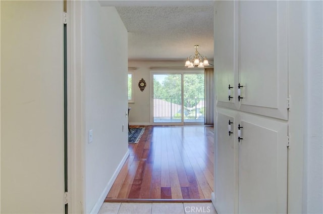 606 Avenida Sevilla Unit O, Laguna Woods, CA 92637 - foyer featuring baseboards, a notable chandelier, wood finished floors, and a textured ceiling