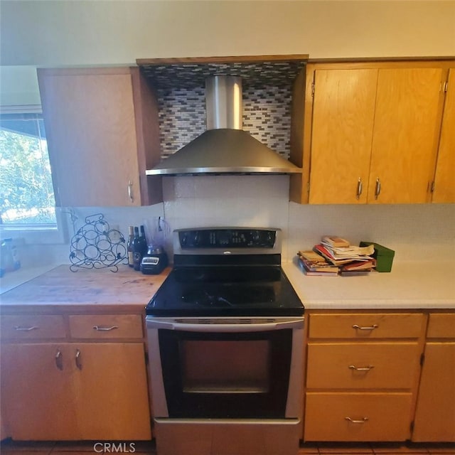 kitchen featuring light countertops, stainless steel electric stove, wall chimney exhaust hood, and tasteful backsplash