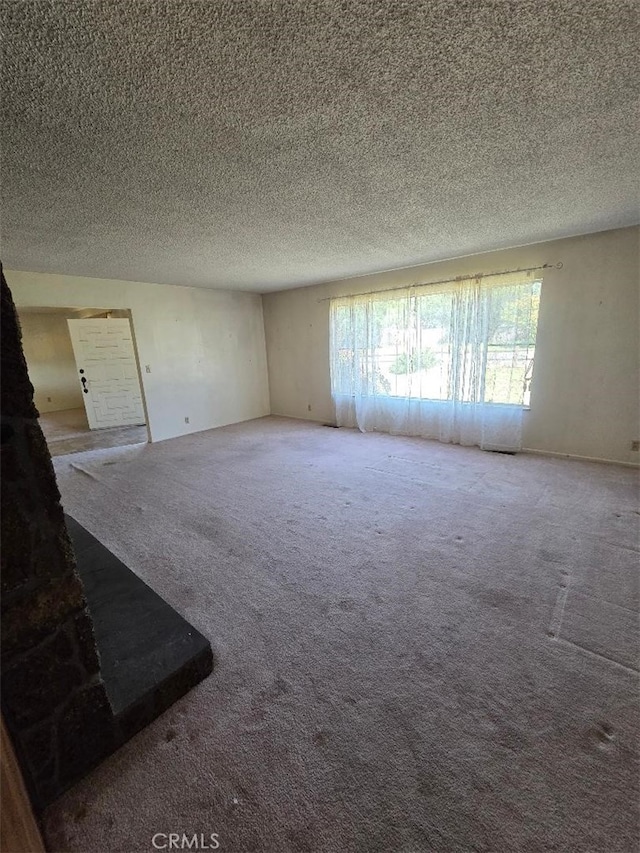 unfurnished living room with carpet flooring and a textured ceiling