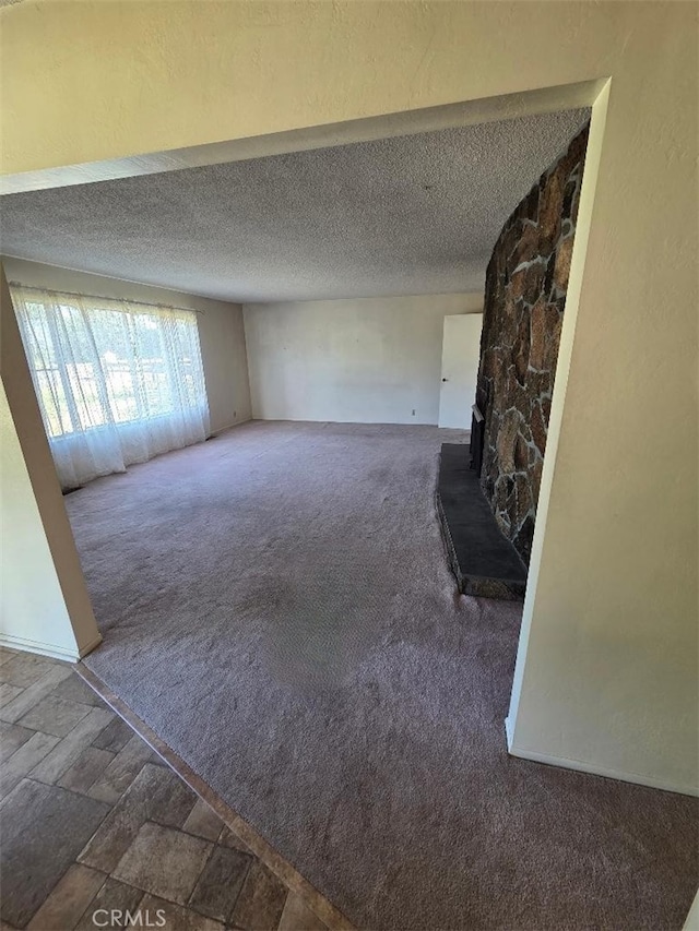 unfurnished living room featuring a textured ceiling and carpet floors