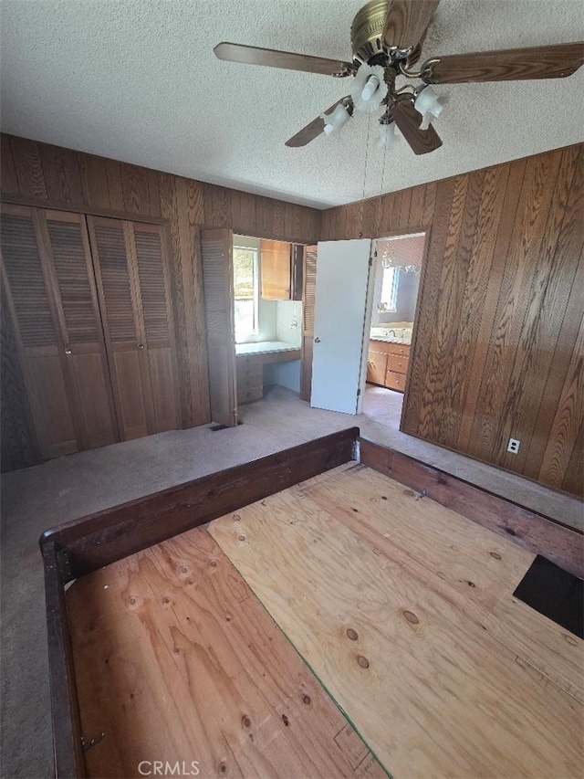 unfurnished bedroom featuring multiple windows, a textured ceiling, wood walls, and ceiling fan