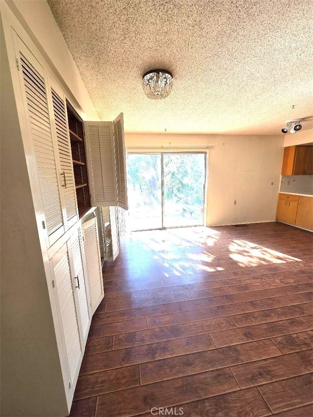 unfurnished living room featuring dark wood-style flooring and a textured ceiling