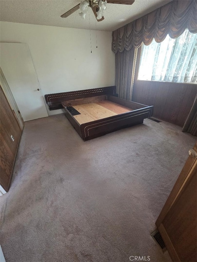 carpeted bedroom featuring a ceiling fan and a textured ceiling