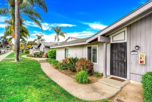 property entrance with a lawn and stucco siding