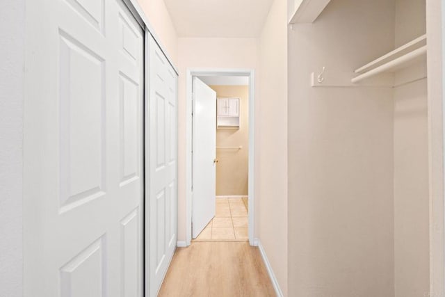 corridor featuring light wood-type flooring and baseboards