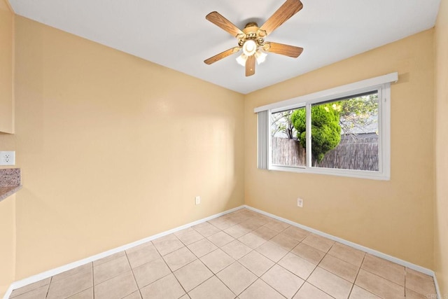 empty room with baseboards, a ceiling fan, and light tile patterned flooring