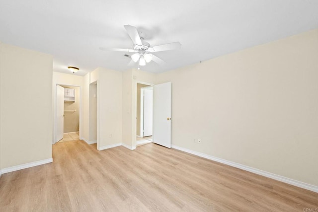 spare room featuring light wood-type flooring, baseboards, and ceiling fan