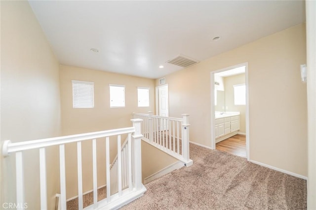 corridor featuring visible vents, a wealth of natural light, an upstairs landing, and carpet