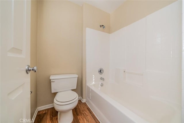 full bath with toilet, wood finished floors, bathing tub / shower combination, and baseboards