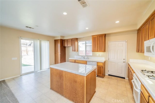 kitchen featuring a sink, visible vents, white appliances, and a kitchen island