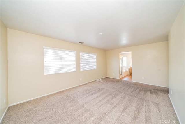 empty room featuring light colored carpet, baseboards, and visible vents