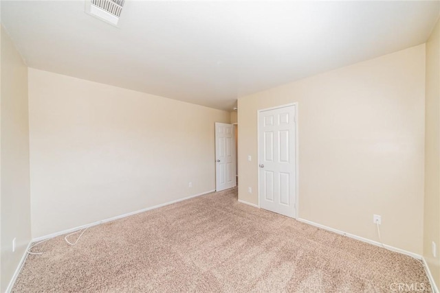 empty room with visible vents, light colored carpet, and baseboards