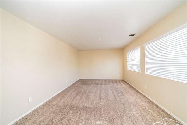 spare room with light colored carpet, baseboards, and visible vents