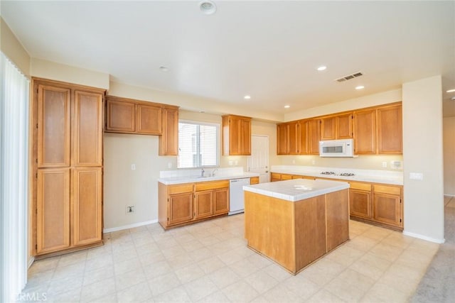 kitchen with recessed lighting, white appliances, a center island, visible vents, and a sink