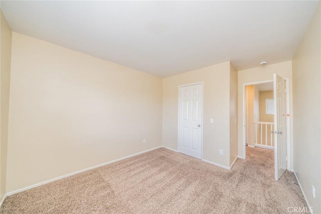 unfurnished bedroom with light colored carpet and baseboards