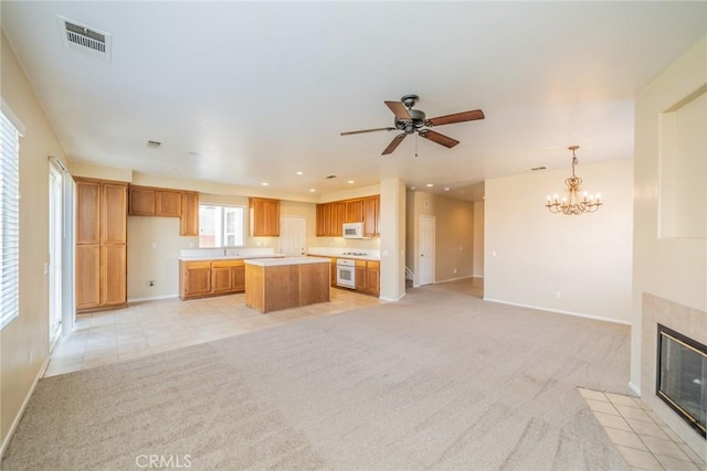 kitchen with light colored carpet, visible vents, a kitchen island, open floor plan, and a tile fireplace