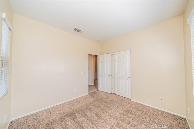 unfurnished bedroom with light carpet, baseboards, and visible vents