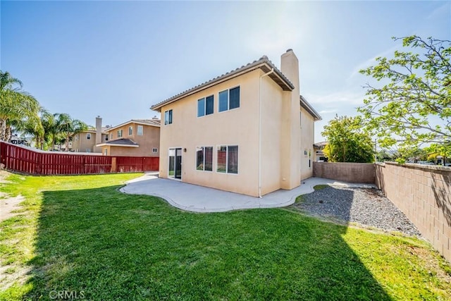 rear view of property featuring a patio, stucco siding, a chimney, a fenced backyard, and a lawn