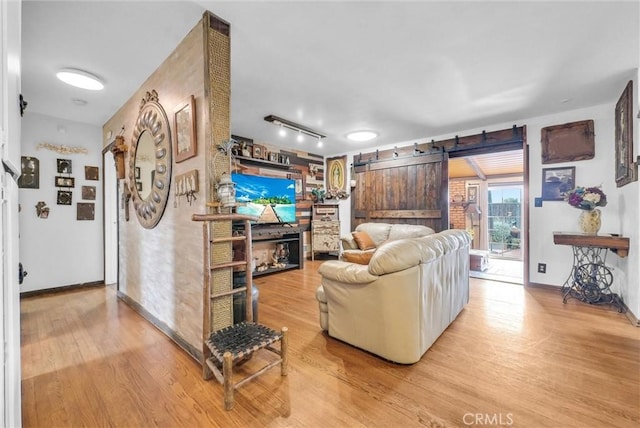living area with baseboards, a barn door, wood finished floors, and a fireplace